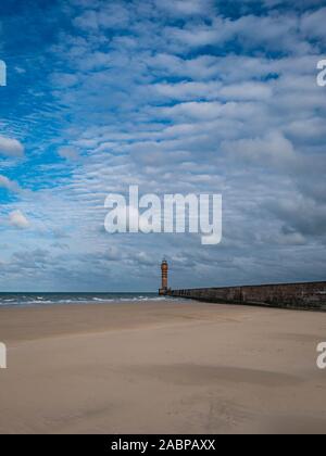 Lighthouse in the distance with pier at the beach leading towards it Stock Photo