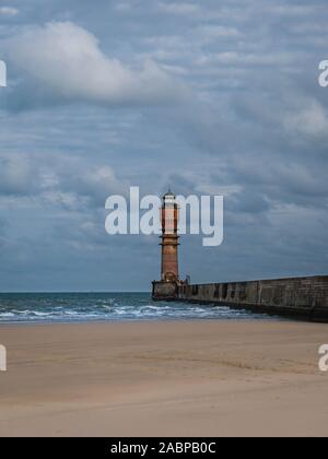 Lighthouse with pier at the beach leading towards it Stock Photo