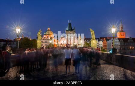 Karluv most, people on the Charles Bridge at dusk, in the back dome of the church Kreuzherrenkirche with old town bridge tower, Prague, Bohemia Stock Photo