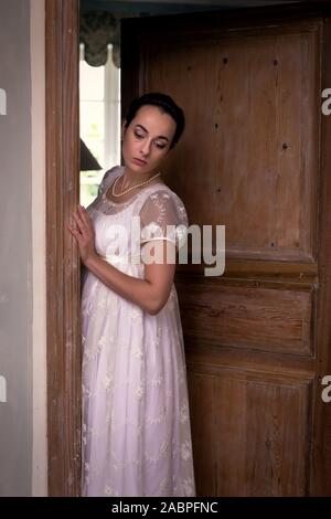 Young lady in authentic regency dress standing in a doorway Stock Photo