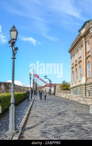 Budapest, Hungary - Nov 6, 2019: Cobbled path along with the Buda Castle palace buildings. Historical palace building, facade with arched windows. Tourist attraction and Hungarian national heritage. Stock Photo