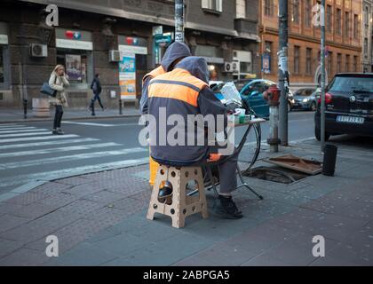 Belgrade, Serbia, Nov 26, 2019: Two repairers connecting fiber optic cables from a manhole in the street Stock Photo
