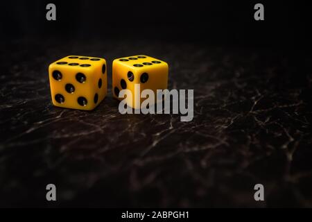 two yellow dice on black textured background Stock Photo