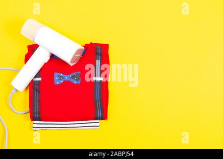 Modern steamer with clothes on yellow background. Handheld clothing accessory, steam iron for ironing clothes, fabric wrinkle remover. Top view Stock Photo