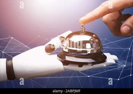 Close-up Of A Person Ringing Service Bell Hold By Robot Against Technology Background Stock Photo