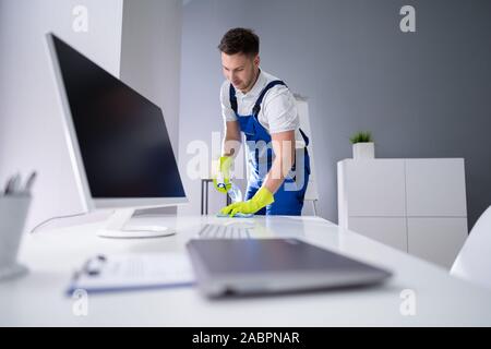 Portrait Of Happy Young Maid Cleaning Glass Table In Office Stock Photo