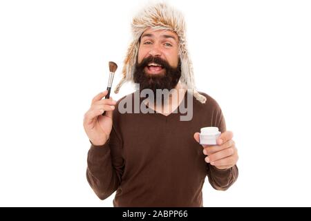 Freak visagiste. Applying makeup face tone. Powder cosmetics. Man bearded stylist wear hat hold brush for makeup. Eccentric guy with beard. Makeup and greasepaint. Natural brush. Stylist career. Stock Photo