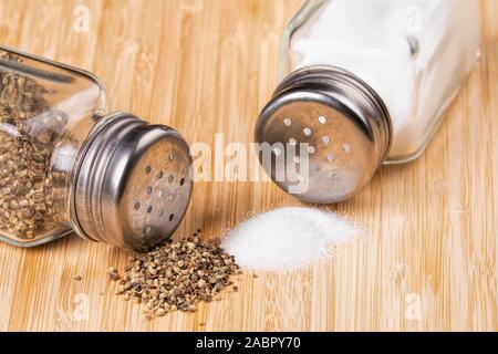 https://l450v.alamy.com/450v/2abpy70/salt-and-pepper-shakers-with-spilled-salt-and-peeper-on-a-wooden-background-2abpy70.jpg
