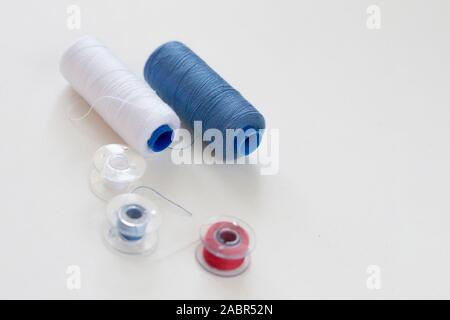 Sewing accessories on a light background close-up. Multi-colored spools of thread Stock Photo