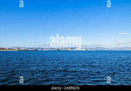 DEC 2, 2018 Hakodate, JAPAN -Hakodate blue harbour bay and industrial port with large cranes and ship mountain view background, Distant view. Stock Photo