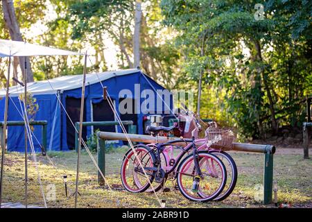 Bicycles leaning against a rail post at a bush camp site in Australia Stock Photo