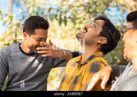 Three young adult laughing and having fun at picnic - Concept of happy friendship - youthful Male friends socializing at college. Stock Photo