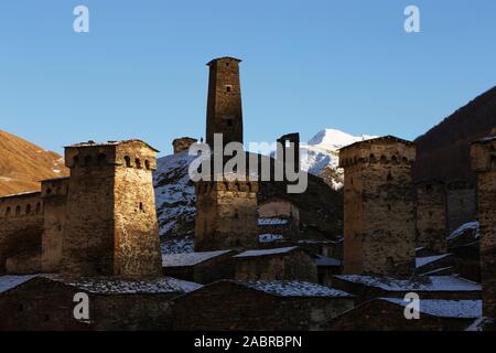 Ancient watchtowers of Svaneti Georgia on a background of snowy mountain peaks. Authentic masonry in the sun Stock Photo