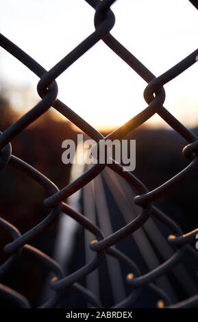 autumn sunset over horizon behind a njtransit train track and fence in Piscataway New Jersey Stock Photo