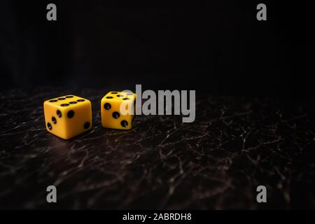 two yellow dice on black textured background Stock Photo