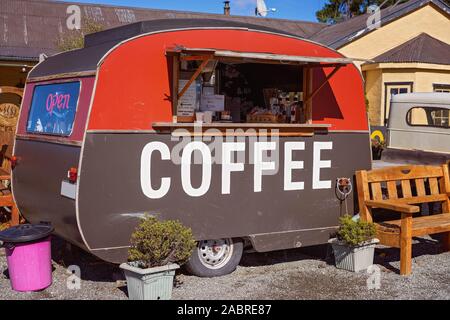 A small old wooden red and brown caravan selling coffee on the side of the road in New Zealand Stock Photo