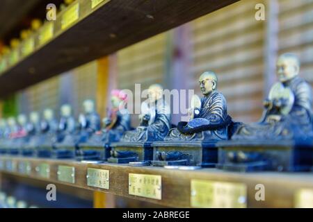 Miyajima, Japan - October 13, 2019: View of Buddhistic statues with coin offering, in the Daisho-in temple complex, in Miyajima (Itsukushima) Island, Stock Photo