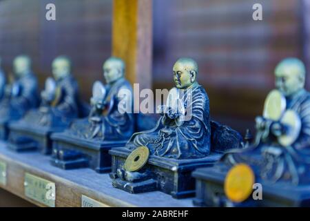 Miyajima, Japan - October 13, 2019: View of Buddhistic statues with coin offering, in the Daisho-in temple complex, in Miyajima (Itsukushima) Island, Stock Photo