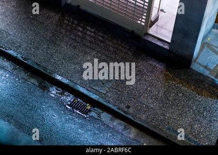 Wet rainy urban outdoor floor scene at night on a bright tarmac road Stock Photo