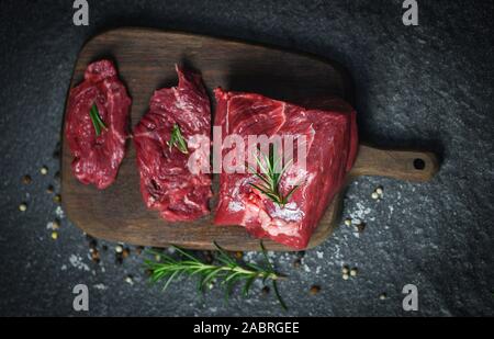 Fresh meat beef sliced on black background / Raw beef steak with herb and spices on wooden cutting board Stock Photo