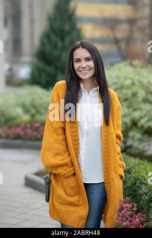 Pleasant walk. Positive young woman putting hands in the pocket while standing on the street Stock Photo