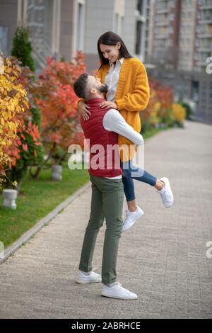 Man in love. Nice strong man holding his girlfriend in his hands while being in love with her Stock Photo