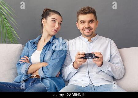 Premium AI Image  bearded boyfriend playing online games with his  beautiful blonde girlfriend sitting on their couch using wireless  controllers