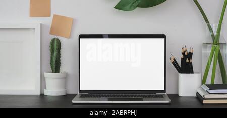 Modern workplace with open blank screen laptop computer with office supplies on black table Stock Photo