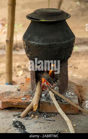 Old cooking pot stove using firewood.Large metal cauldron over a fire in a outdoor kitchen Stock Photo