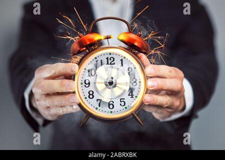 Businessman holding an alarm clock that's out of control
