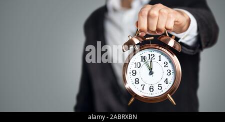 Businessman holding a clock that shows five to twelve Stock Photo