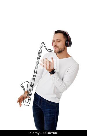handsome young man in headphones listening to music and playing an imaginary saxophone isolated on white background. Stock Photo