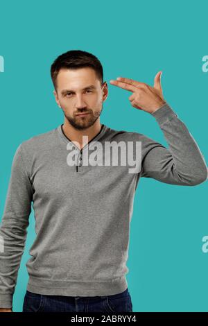 bearded man shooting in temple with hand isolated on blue background. Stock Photo