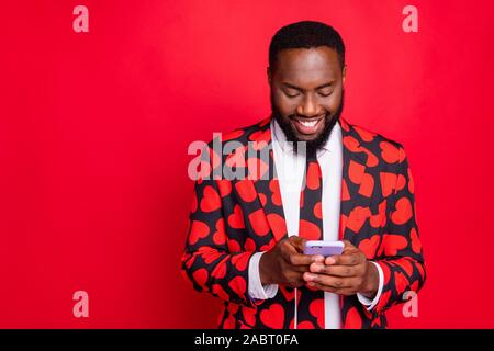 Photo of funny dark skin guy holding telephone chatting with girlfriend write love sms letter wear stylish hearts pattern suit blazer shirt necktie Stock Photo