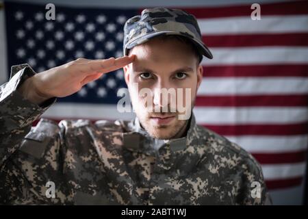 Portrait Of Army Soldier Saluting In Front Of American Flag Stock Photo