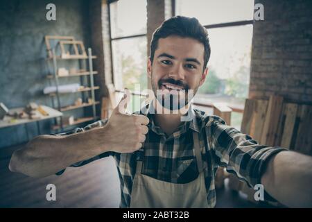 Closeup photo of handsome guy master raising thumb up making selfies in new own wooden business industry studio looking customers woodwork shop garage Stock Photo