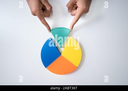High Angle View Of Businessperson's Hand Placing A Last Piece Into Pie Chart Stock Photo