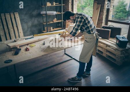Top above high angle full length photo of focused professional workman use screwdriver fix shelf on tabletop in home house garage Stock Photo