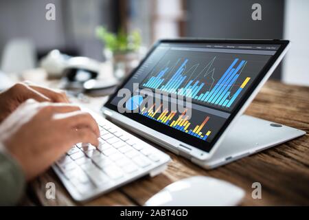 Close-up Of Businessperson Pointing At Graph On Digital Laptop In Office Stock Photo