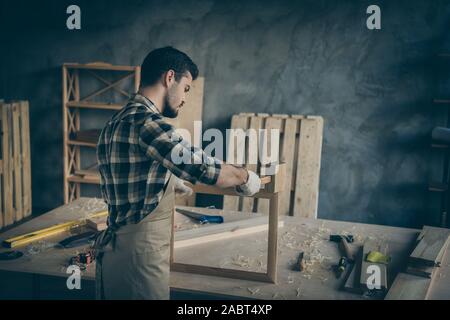 Back rear view photo of serious confident man using hammer to finish making wooden frame ordered Stock Photo