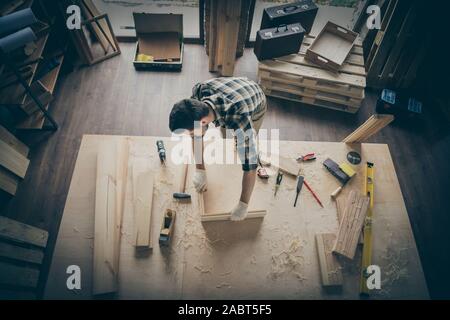 Top above high angle view photo of pensive thougthful craftsman making frame with wooden blocks surrounded with instruments Stock Photo