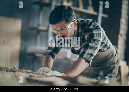 Portrait of his he nice attractive focused concentrated skilled experienced hardworking guy builder carving wood creating furniture at modern Stock Photo