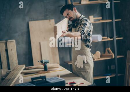 Portrait of his he nice attractive focused skilled hardworking guy looking measuring smooth board plank at home modern industrial loft brick style Stock Photo