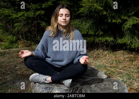 Young woman meditating on a tree stump in France. Stock Photo