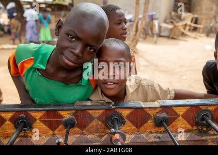 Togolese boys leaning on a table football in Korbongou, Togo. Stock Photo