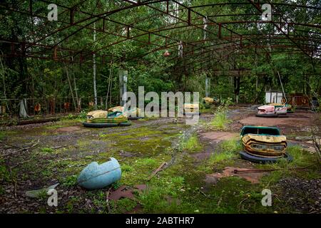 Old broken children's electric cars in an amusement park, a recreation park in the city of Pripyat. Chernobyl nuclear power plant exclusion zone Stock Photo