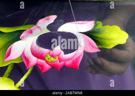 Young female workers doing embroidery. Flower. Close-up on hand.  Hue. Vietnam. Stock Photo