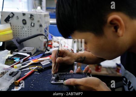 Mobile phone repair. Man is changing a broken mobile phone display in the service.  Hoi An. Vietnam. Stock Photo