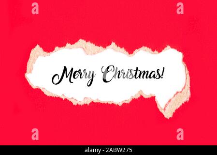 Words Merry Christmas on white background under torn red paper. Christmas concept. Stock Photo