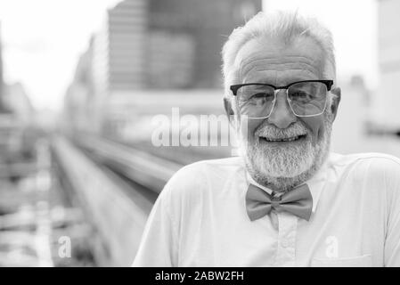Handsome bearded senior tourist man exploring the city in black and white Stock Photo